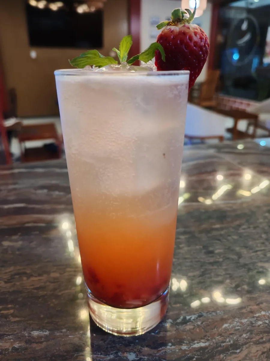 Cóctel tropical de frutas con degradado y fresa en barra de Guayusa